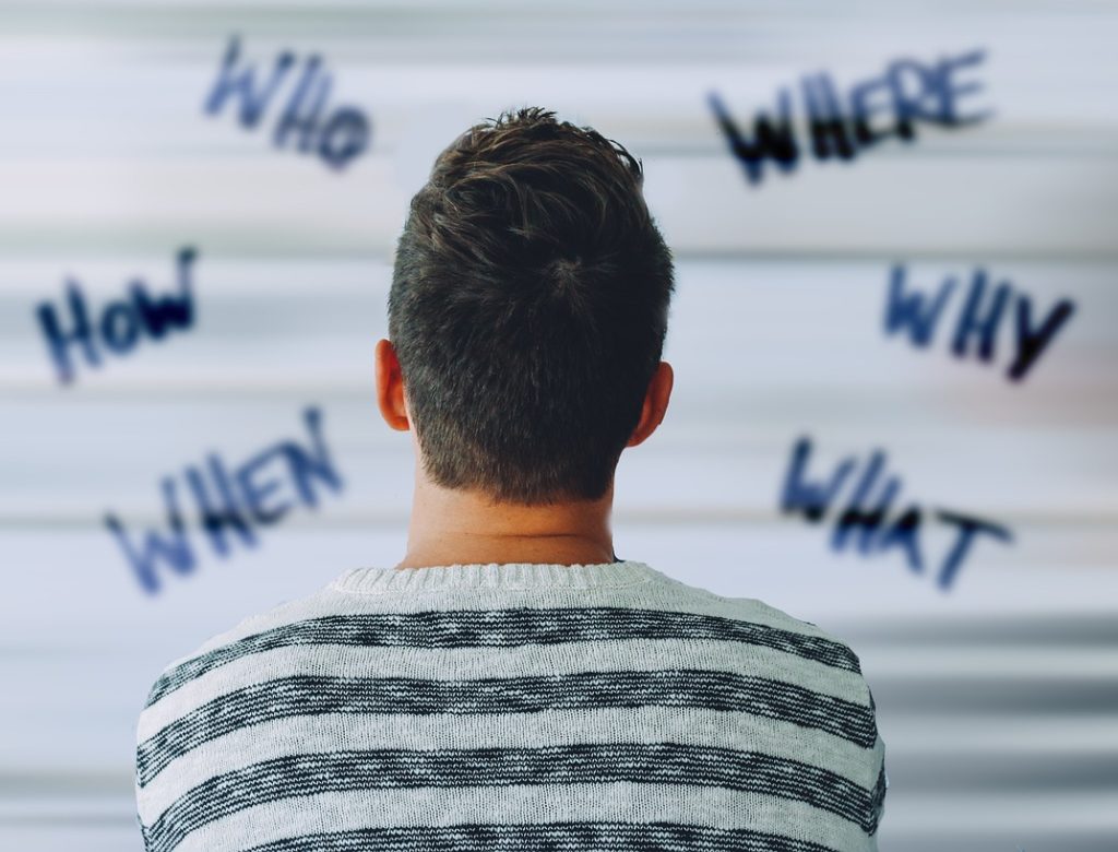 Man looking at a wall with questions written all over it